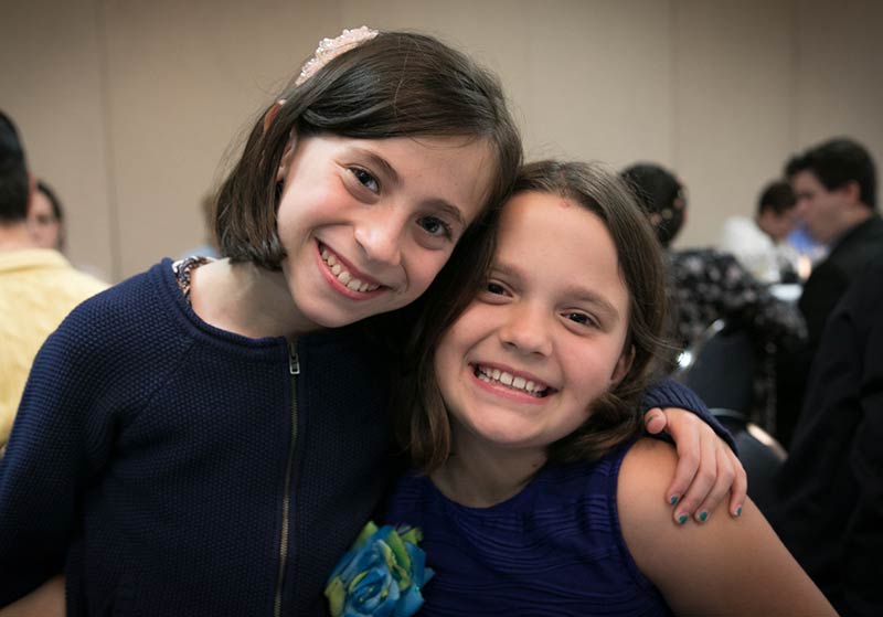 Image of two 4th grade girls holding each other and smiling.